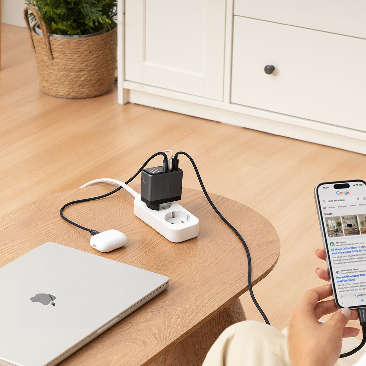 EnoVolt Pro 70W plugged into a power strip, charging a laptop, earbuds and a phone in a living room