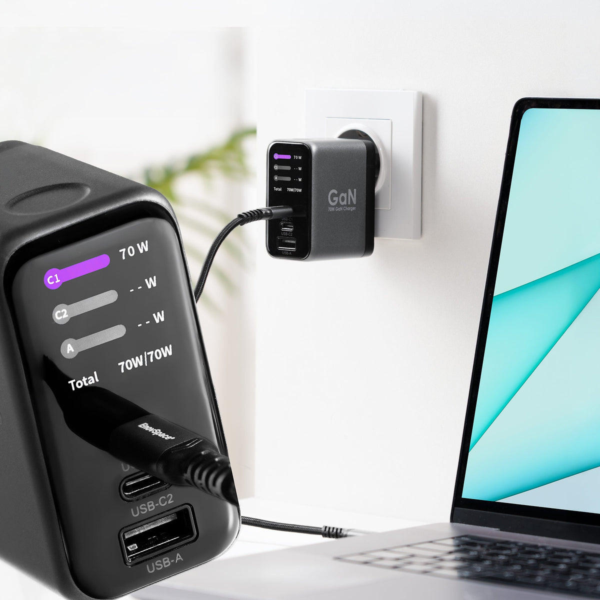 EnoVolt Pro 70W TFT display showing 70W delivered live, next to a laptop on a desk